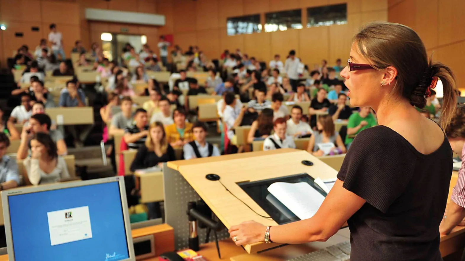 A female lecturer speaks to a group of students in an auditorium