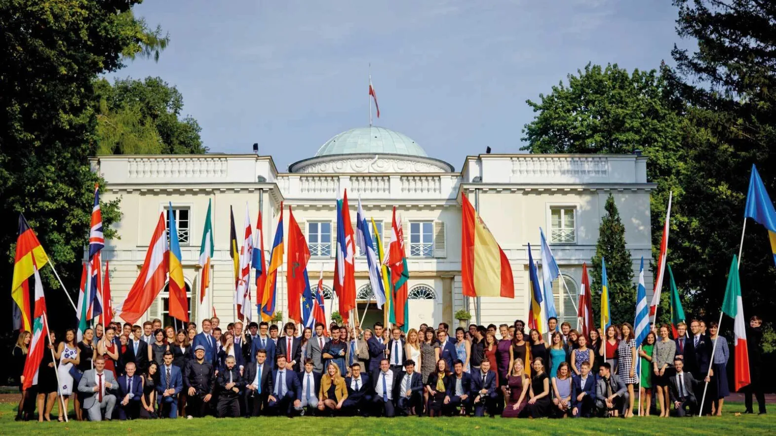 Group of people posing with large flags of multiple countries