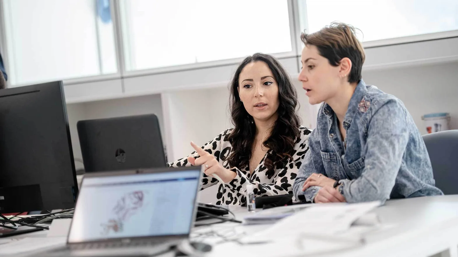 Situation de travail: deux femmes discutent devant un écran d'ordinateur