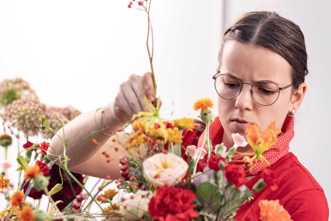 Une jeune femme compose un bouquet de fleurs