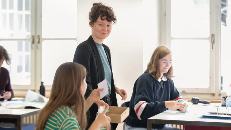 Une enseignante et deux élèves dans une salle de classe.