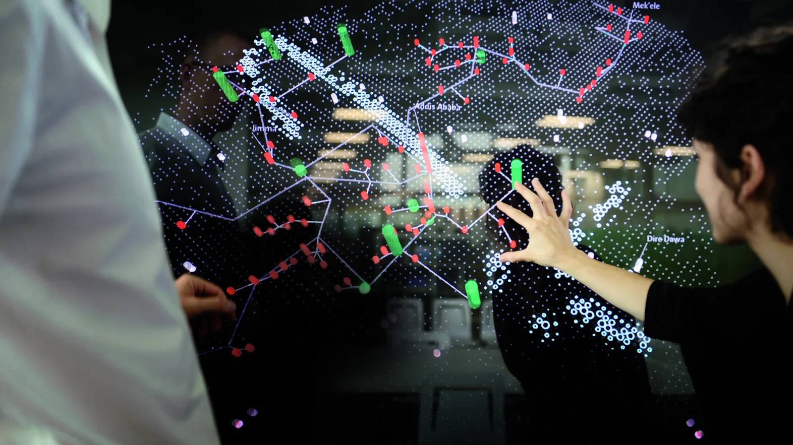 A woman indicates something on a screen with a map of a smart city.