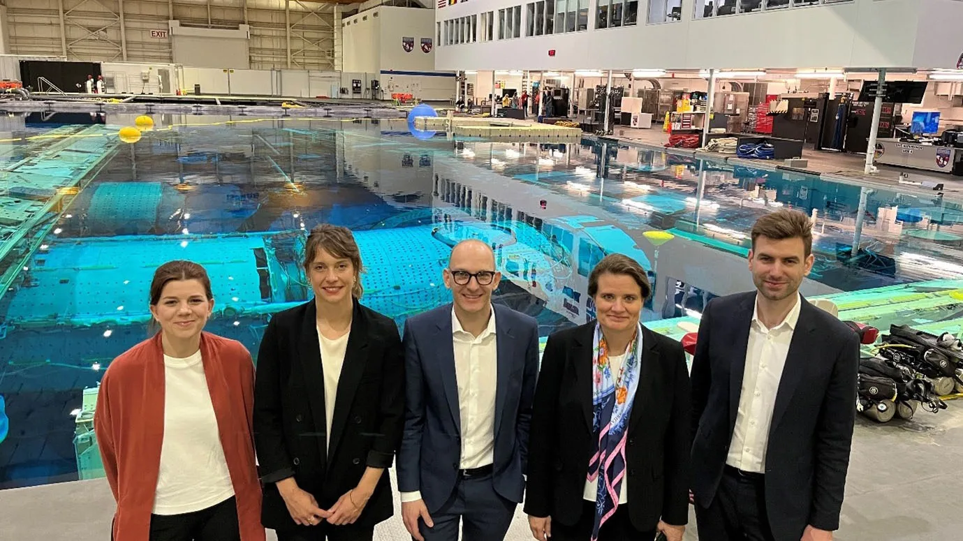 Le secrétaire d'État Hirayama (deuxième à droite) et d'autres délégués du SEFRI devant une piscine du Neutral Buoyancy Laboratory.