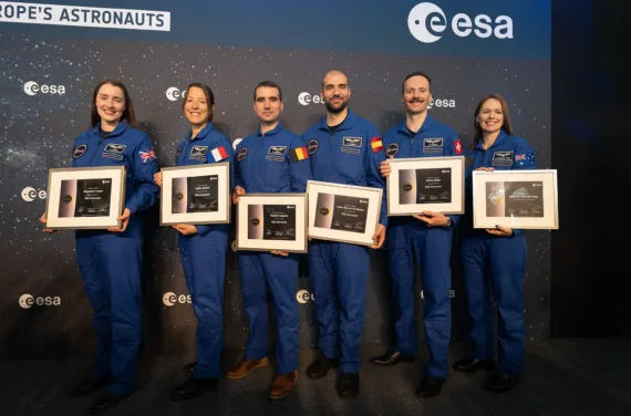 Die ESA-Astronauten posieren für ein Gruppenfoto in blauen Overalls mit ihren Abschlussdiplomen.