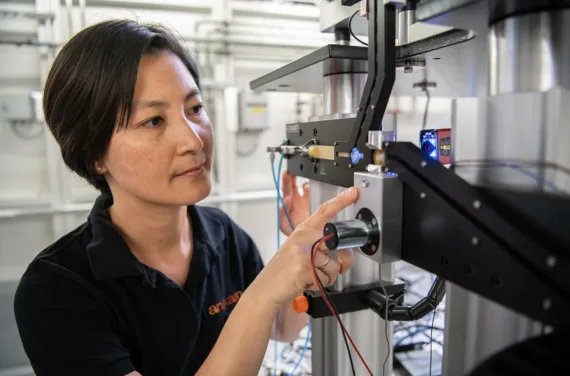 A woman in a black T-shirt operates a silver machine.