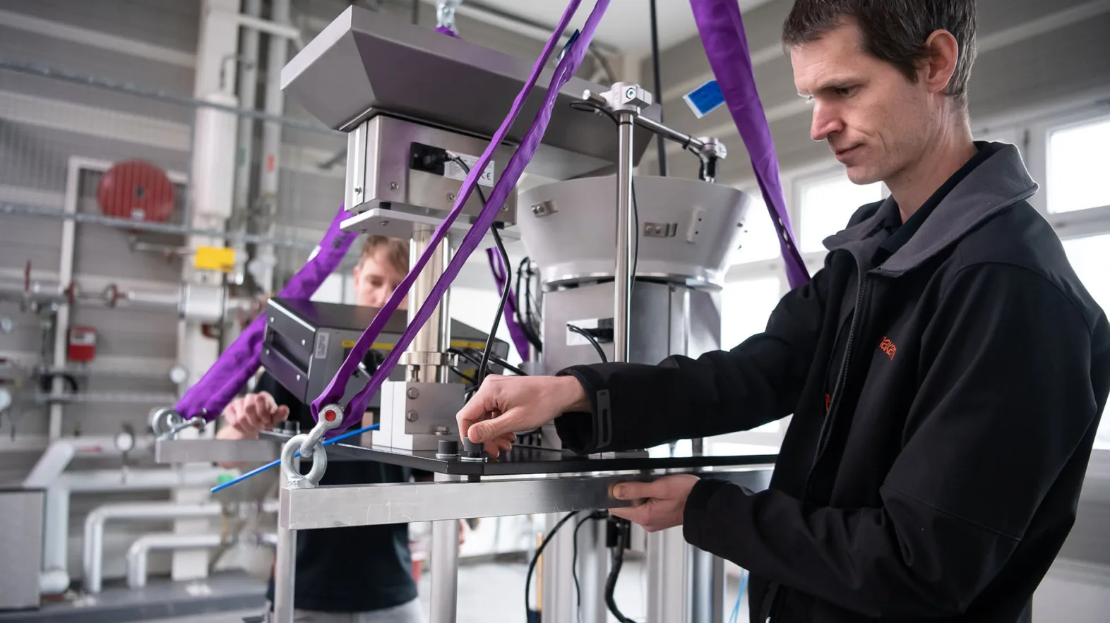 Two men work on metal appliances.