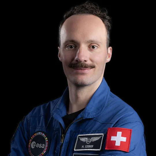 Porträt von Marco Sieber im blauen Anzug der ESA-Astronauten.