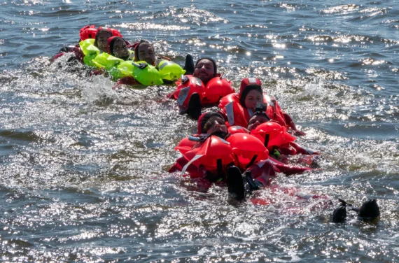 The astronauts float in the sea wearing life jackets.