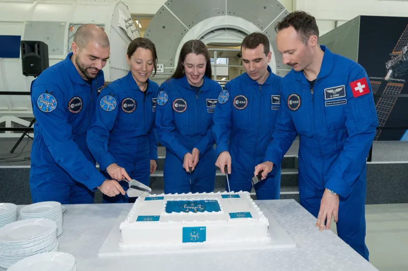 Die fünf ESA-Astronautinnen und -Astronauten schneiden gemeinsam ihren Kuchen zur absolvierten Grundausbildung an.