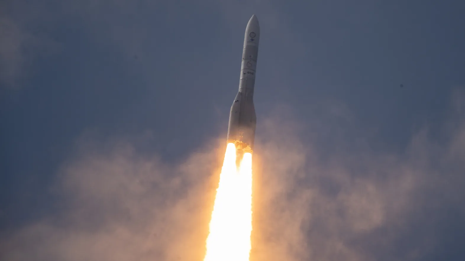 The Ariane 6 in flight against a night sky and with a trail of fire behind her.