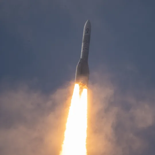 The Ariane 6 in flight against a night sky and with a trail of fire behind her.