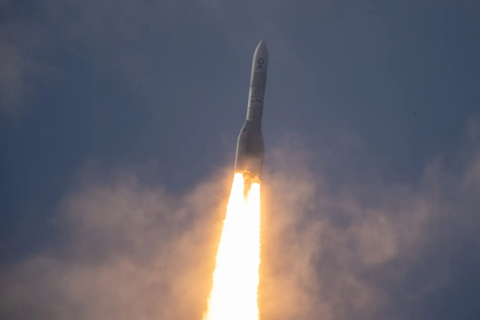 Ariane 6 en vol sur fond de ciel nocturne et avec une traînée de feu derrière elle.