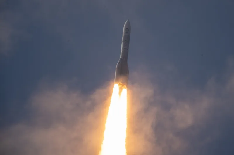 Die Ariane 6 im Flug vor einem nächtlichen Himmel und mit einer Feuerspur im Rücken.