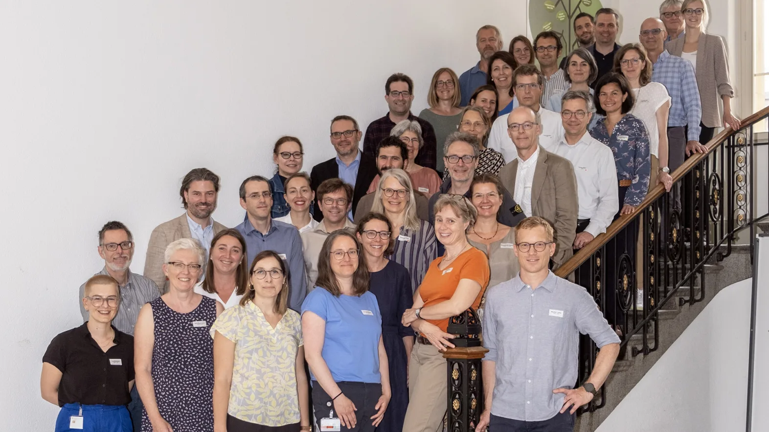 Eine Gruppe von Menschen posiert auf einer Treppe in einem Treppenhaus für ein Gruppenfoto.