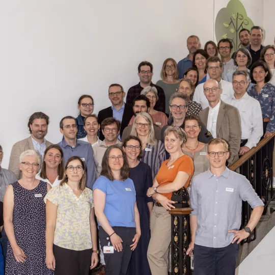 A group of people pose for a group photo on a staircase in a stairwell.