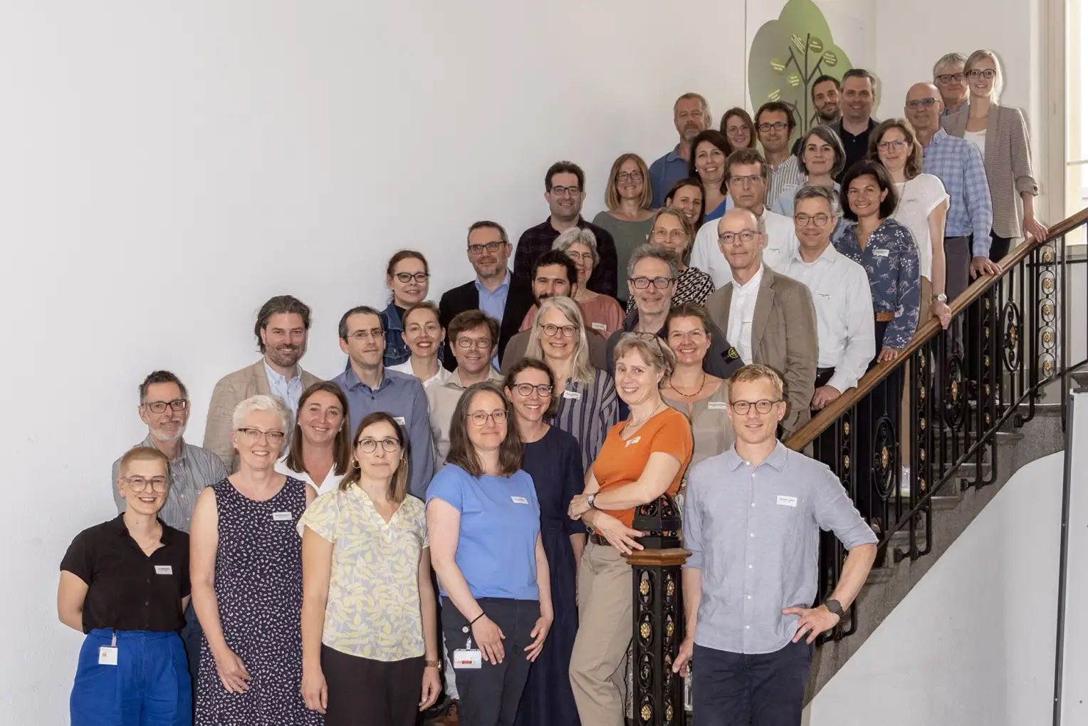 Eine Gruppe von Menschen posiert auf einer Treppe in einem Treppenhaus für ein Gruppenfoto.