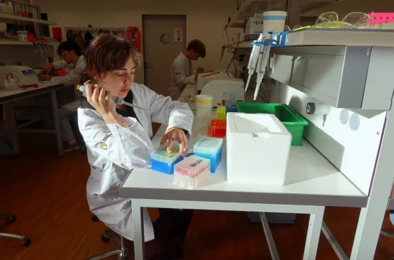 A young girl experiments in a laboratory with a pipette and liquid.