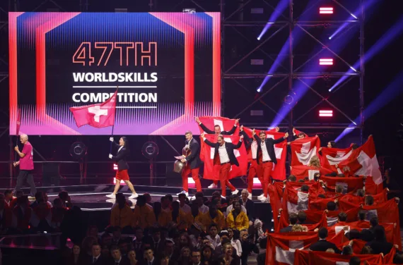 Das Schweizer Team läuft mit grossen Schweizer Fahnen auf die Bühne. Im Hintergrund steht "47th WorldSkills Competition".