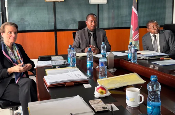 Two men and a woman are sitting at a conference table and listening attentively.