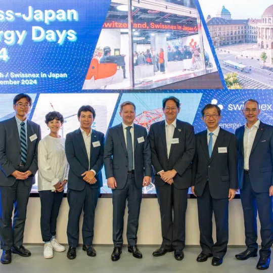 Group photo of seven people in front of a very large screen.