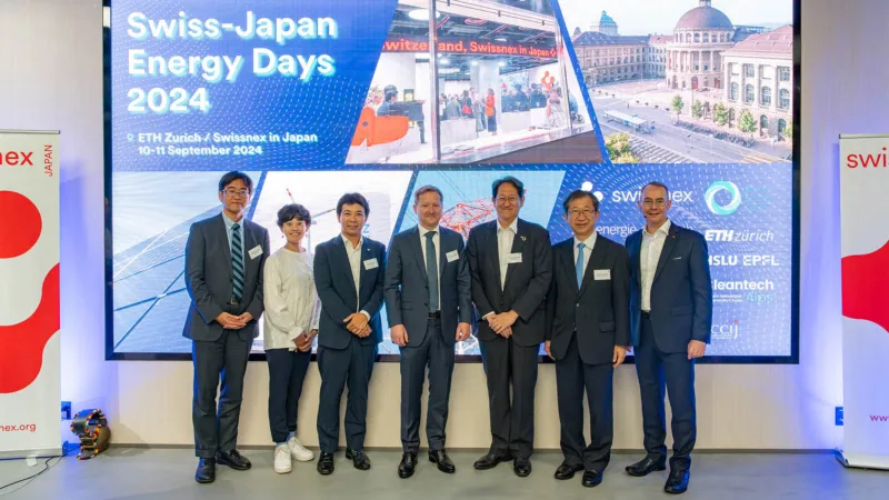 Group photo of seven people in front of a very large screen.