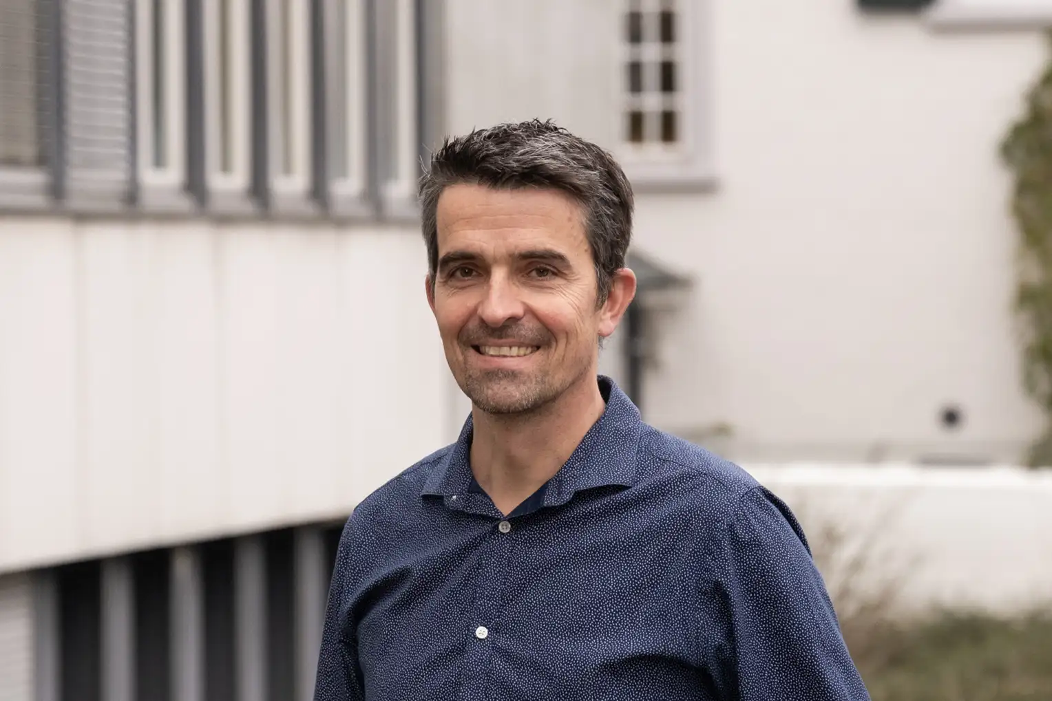 Florian Berset is wearing a blue shirt and standing in front of the SERI building.