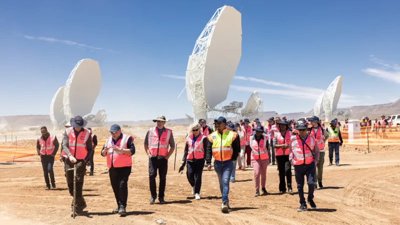 Un groupe de personnes en gilets pare-balles se tient devant plusieurs antennes