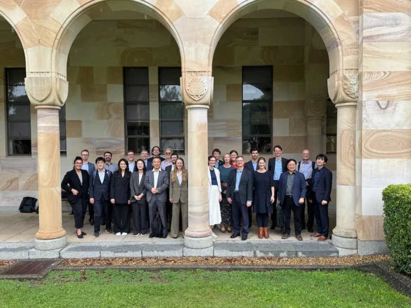 Un groupe de personnes se tient sous une arche en pierre et regarde vers l'appareil photo.