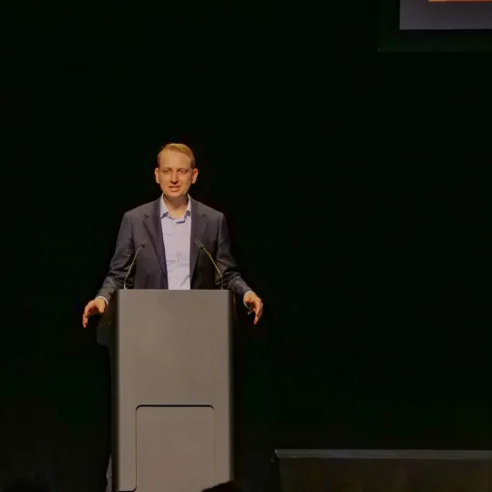 Brendan Karch, interim CEO of Boston and New York, stands on stage and gives a speech.