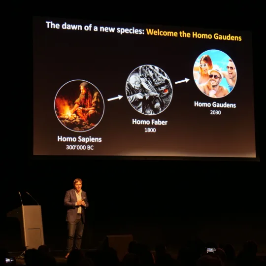 Pascal Kaufmann, neuroscientist and entrepreneur, stands on stage with a presentation behind him.