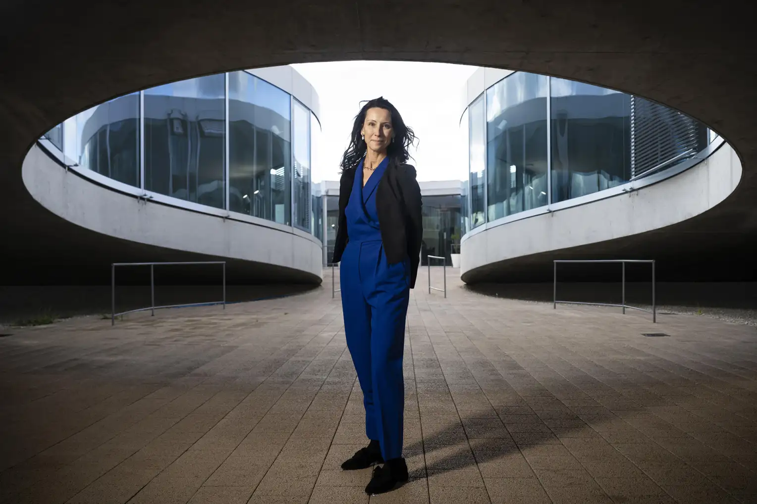 Une femme devant un bâtiment, vêtue d'une combinaison bleue.