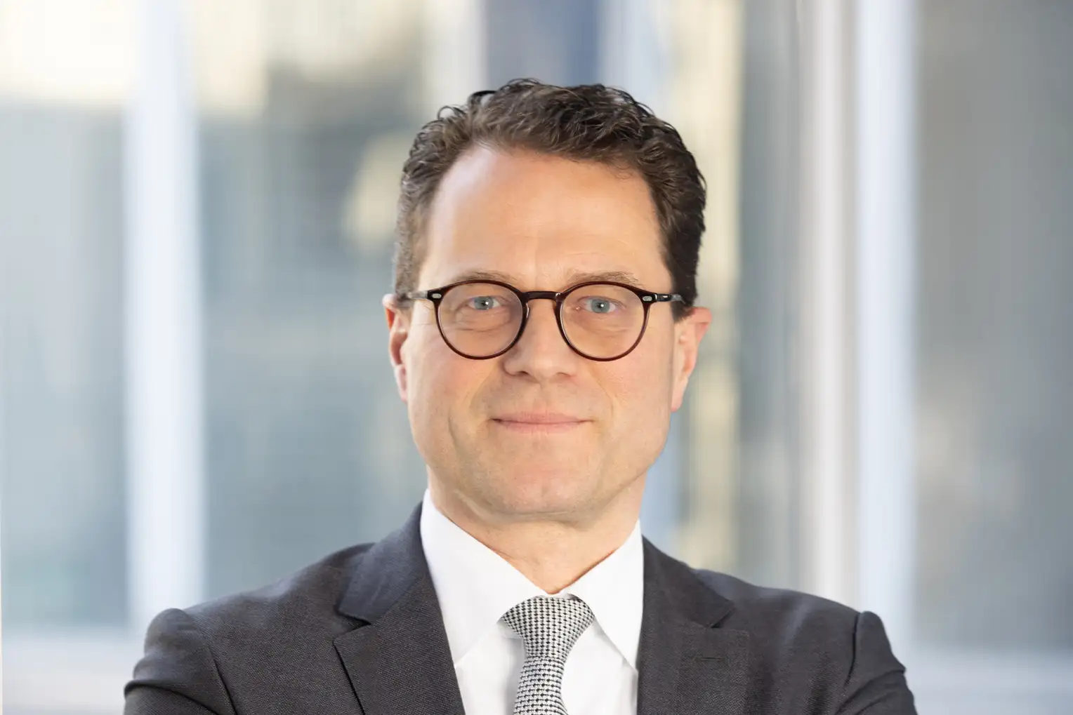 Porträt eines Mannes im Anzug und mit Brille.