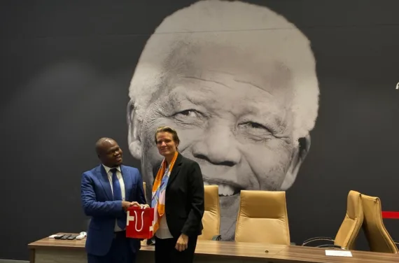 National Research Foundation 25 09 2025 Un homme et une femme se serrent la main devant une effigie de Nelson Mandela.