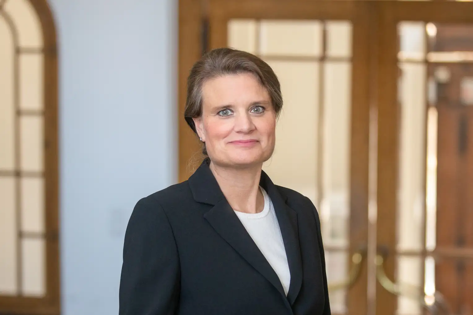 Eine Frau in einem Blazer, die in die Kamera lächelt.