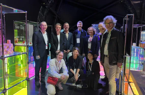 A group of people stand between coloured light installations.