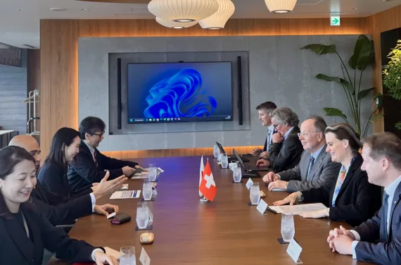 A long conference table with several people seated on each side.
