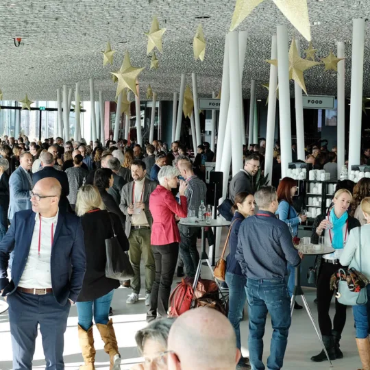 Groupe de personnes autour de tables hautes.