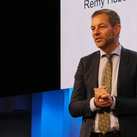 Un homme s'adresse à un public qui n'apparaît pas sur la photo.