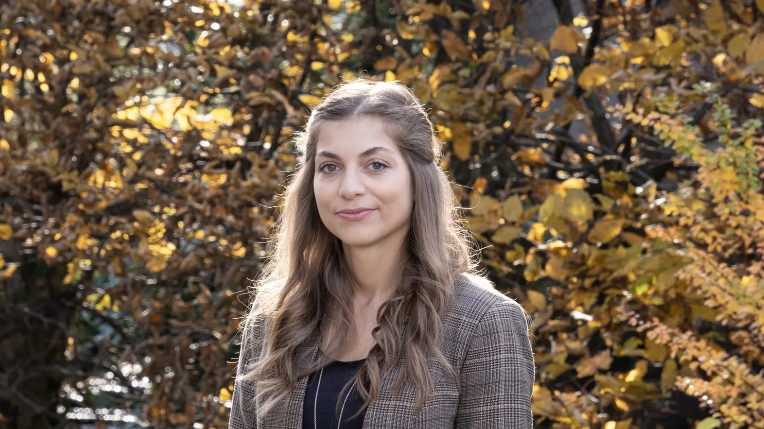 Une femme aux longs cheveux bruns sourit à la caméra.