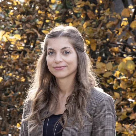 Une femme aux longs cheveux bruns sourit à la caméra.