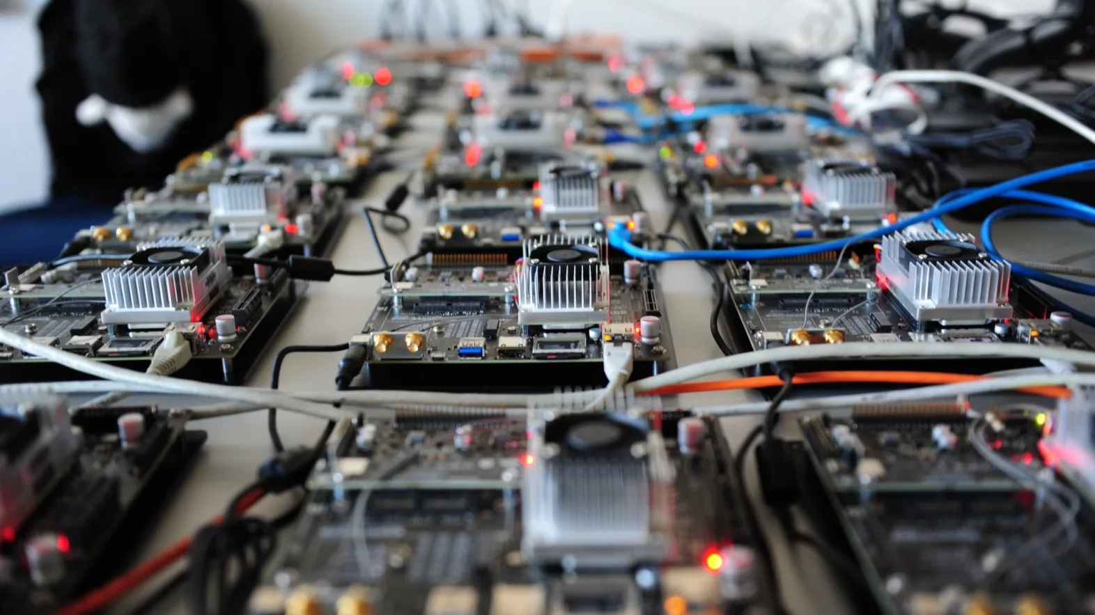 De nombreuses petites cartes électroniques avec des câbles et des lumières clignotantes sont disposées les unes à côté des autres sur une table.