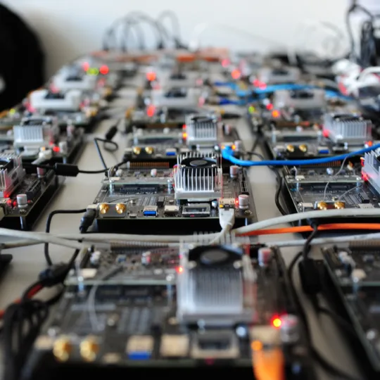 De nombreuses petites cartes électroniques avec des câbles et des lumières clignotantes sont disposées les unes à côté des autres sur une table.