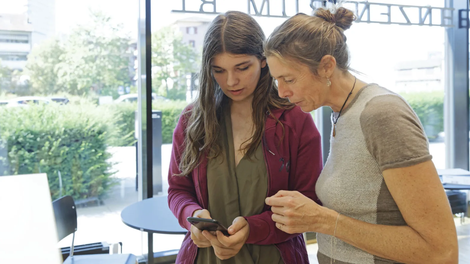 Zwei Frauen die gemeinsam auf ein Handy schauen.