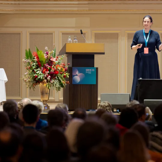 Eine Frau mit einem langen Rock hält eine Rede.