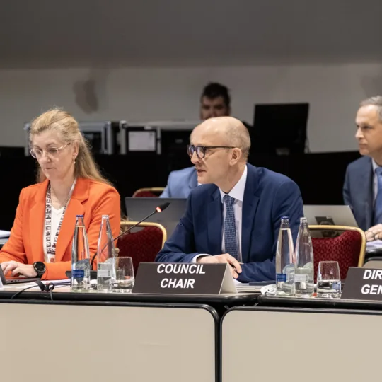 Plusieurs personnes sont assises à un pupitre devant lequel sont posés des badges nominatifs.