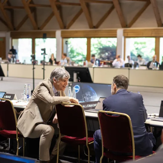 Deux personnes en pleine discussion dans une grande salle de réunion.