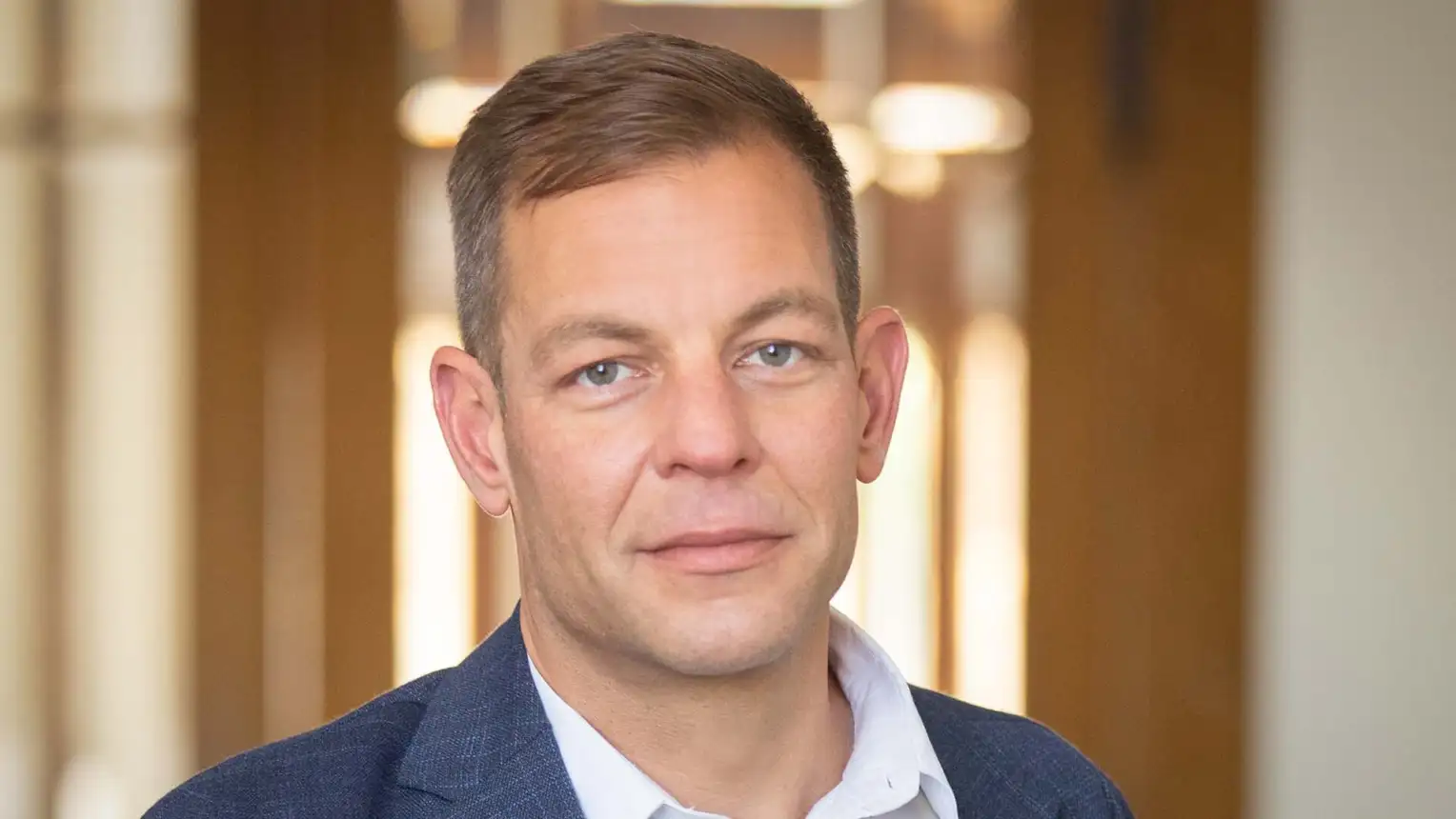 Ein Mann im Anzug steht vor einer Holztür